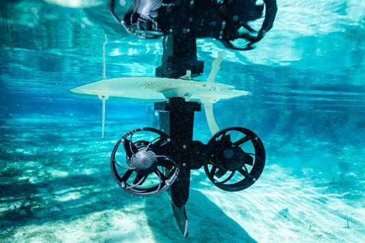 Underwater close-up of a paddleboard motorized fin with dual electric thrusters in clear blue water.”