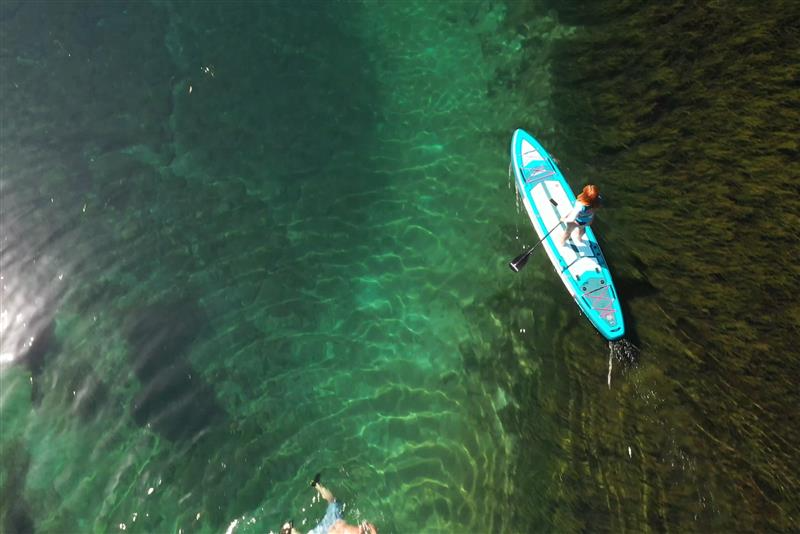 Paddle boarder enjoying sunny San Diego waters with city skyline and coastline views, highlighting top paddle boarding spots in California